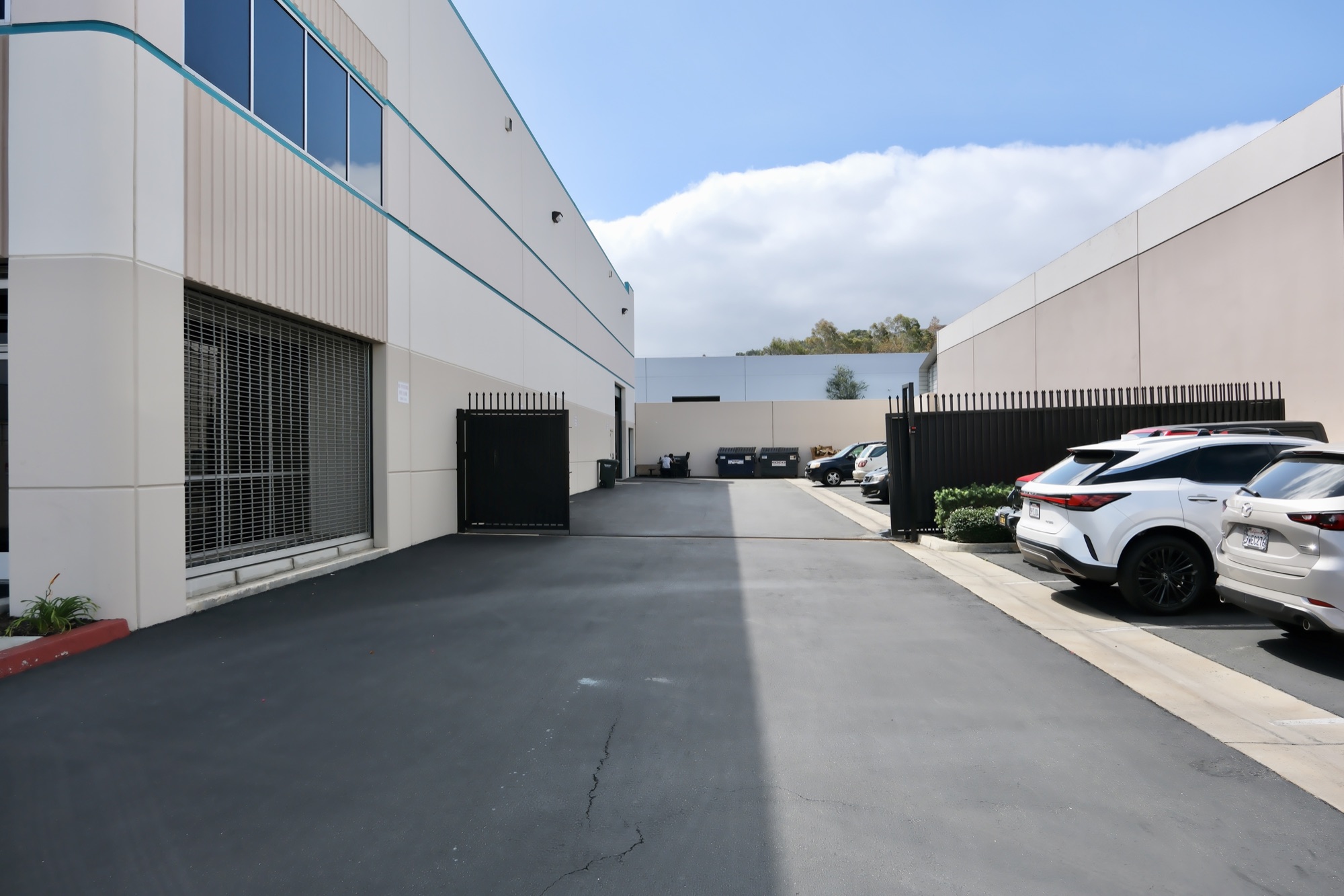 Rear loading area and gated yard behind 2695 Temple Ave with dumpster enclosure and tenant parking